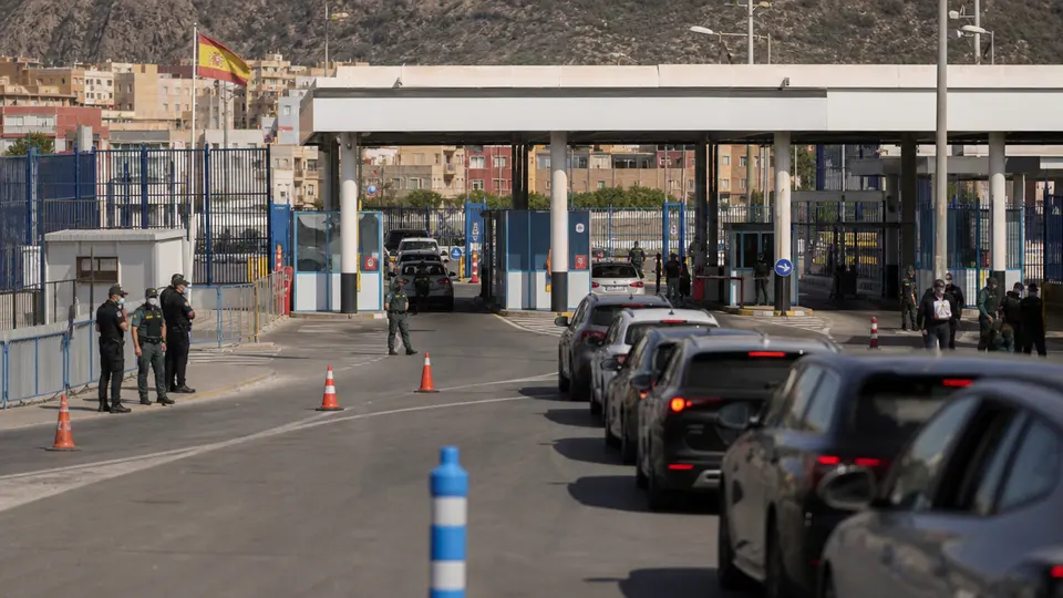 Border checkpoint between Italy and Spain with vehicles queuing under official signage