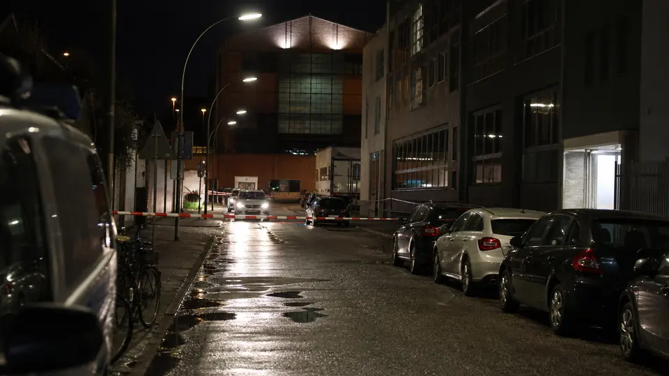 Heavily armed police officers in tactical gear securing the entrance to a factory complex in Hamburg's Schanzenviertel at night