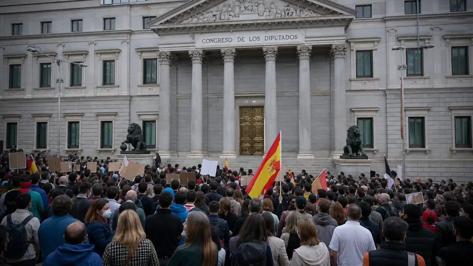 Crowds carrying Spanish and Ceuta flags at a public square demonstration during the Día de Ceuta migration-crisis rallies.
