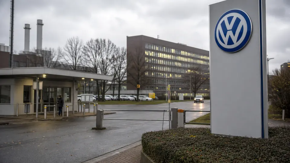 Volkswagen factory floor with assembly line workers and partially built vehicles, representing the automaker's ongoing industrial restructuring.